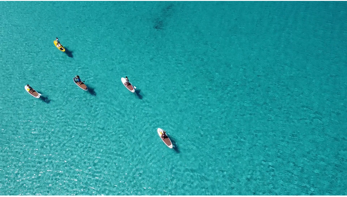 Vista dall'alto del mare cristallino del Gran Pevero e i SUP, con il Drone